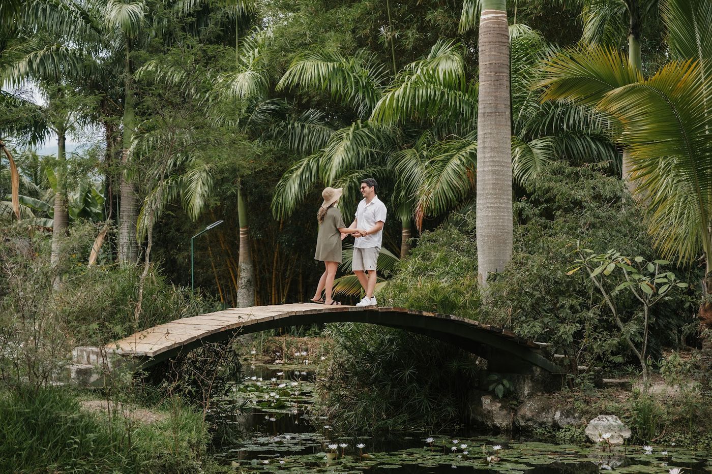 Puente de piedra sobre estanque rodeado de palmeras en Inti Kamari Lodge
